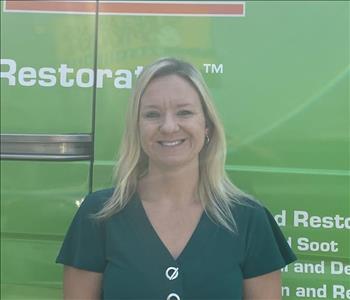 Blonde lady in front of green SERVPRO van